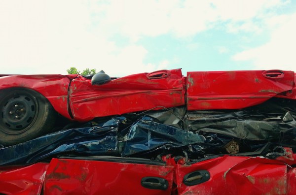 three stacked, crushed cars in a junkyard