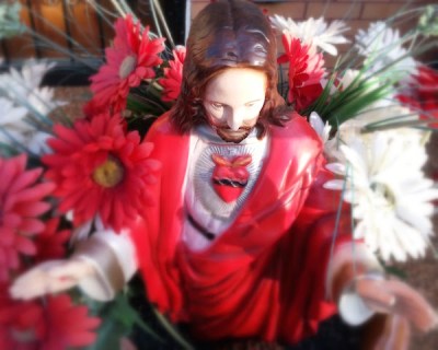 Flower pot with red and white flowers and statue of Jesus