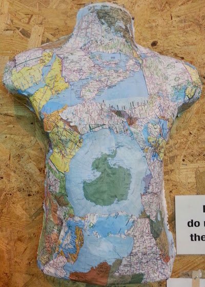 sculpture of human torso with world map glued to it