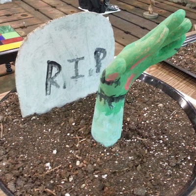 sculpture of zombie hand and grave stone in dirt