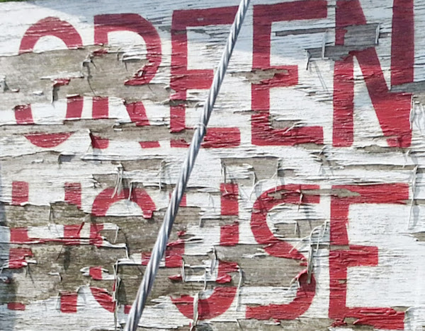 worn painted wooden sign reading "Greenhouse"