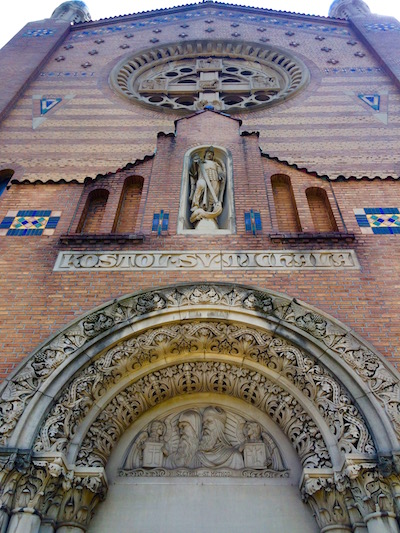 Front of St. Michael Church featuring tympanum, figure in a niche, and rose window