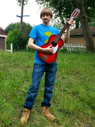 Weird Paul outside with an acoustic guitar