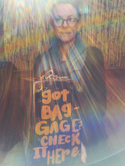 Daria Sandburg holding metal case with painted words "Got baggage? Check it here."