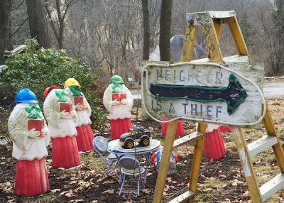 Handmade wooden sign with arrow reading "Neighbor is a Thief" with choir member lawn ornaments missing heads, Ross Township, PA