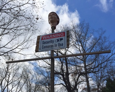 Plastic head on cross with "Security cameras in use" sign, Ross Township, PA