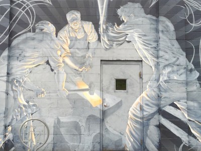 Mural painted on cinderblock wall of iron workers hammering hot steel on an anvil, Red Star Iron Works, Millvale, PA