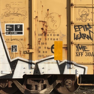 yellow boxcar with graffiti of a mountain range