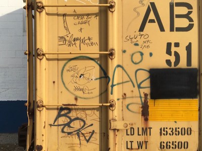 yellow boxcar with graffiti of a cartoon man smoking cigarette