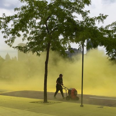 man pushing an electric blower kicking up yellow dust from The Color Run, Pittsburgh, PA