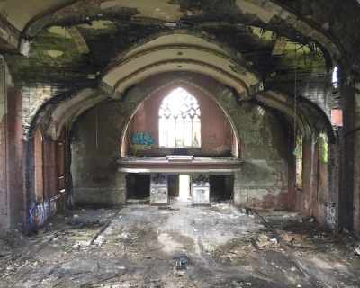 interior of former Holy Trinity Catholic church with spray paint graffiti and sky visible through the roof, Duquesne, PA