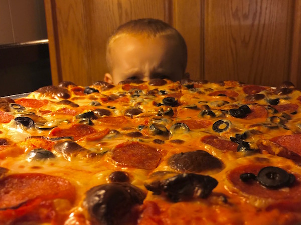 child's head seen over a large pepperoni and olive pizza, P&M Pizza, Arnold, PA