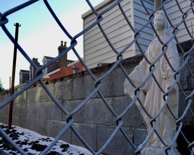 Mary statuette seen through chainlink fence, Pittsburgh, PA