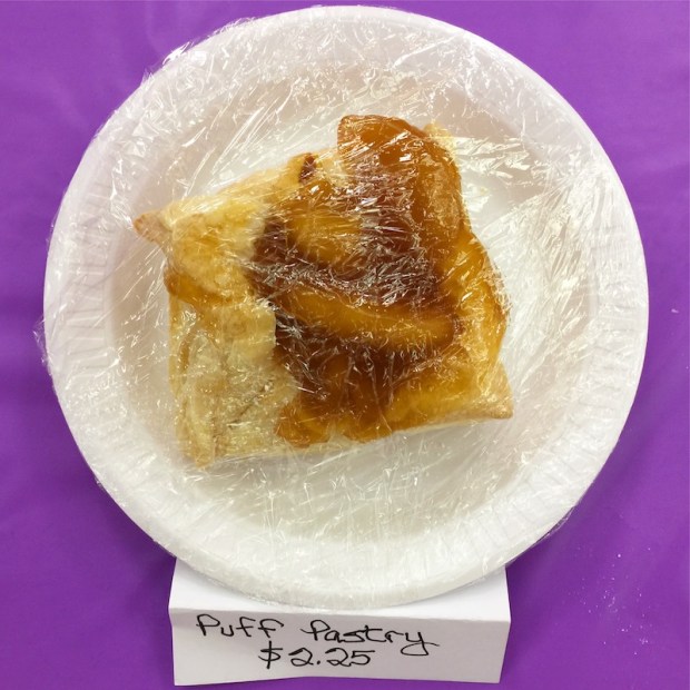 piece of puff pastry in plastic wrap on disposable plate