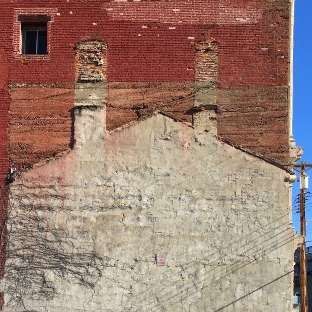 outline of previously-existing "ghost house" against larger brick building, Pittsburgh, PA