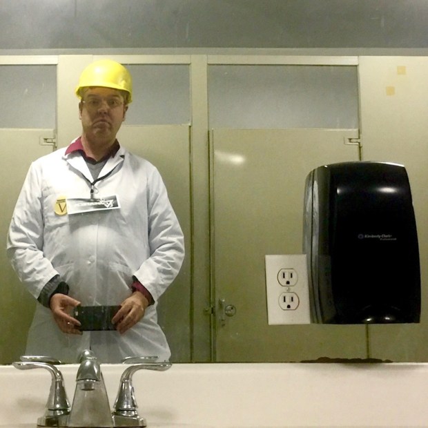 man in lab coat and hard hat in employee restroom