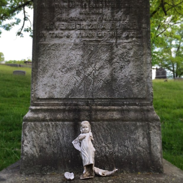 broken porcelain doll on base of marble grave monument, Allegheny Cemetery, Pittsburgh, PA