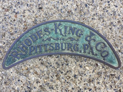 brass plate embedded in sidewalk concrete advertising Rhodes-King & Company, Pittsburgh, PA