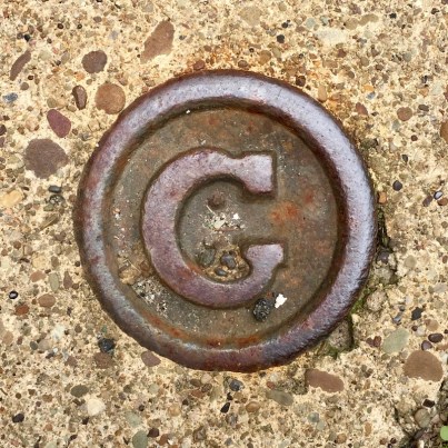 round steel sidewalk plaque with letter "G", Pittsburgh, PA