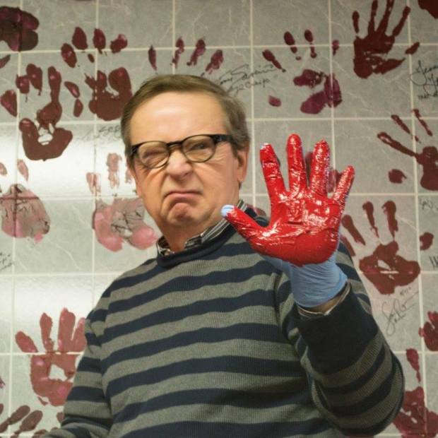 John Kirch with left hand painted blood red, preparing to leave a hand print on wall