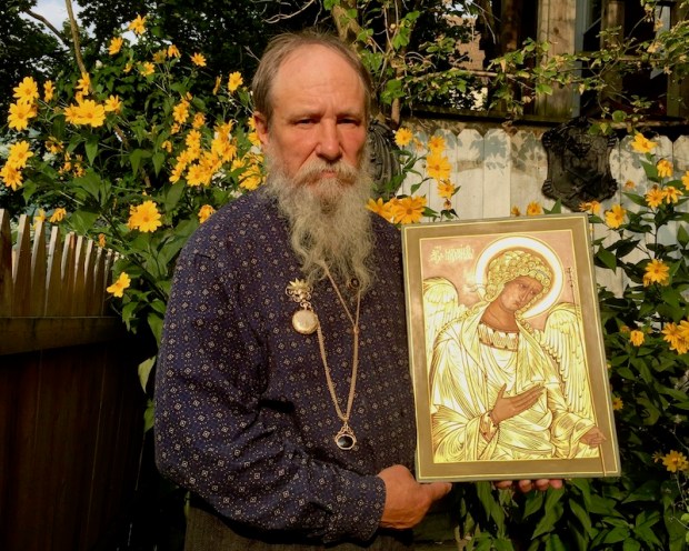 icon painter Simeon Larivonovoff holding a glowing icon of the Arcangel Michael