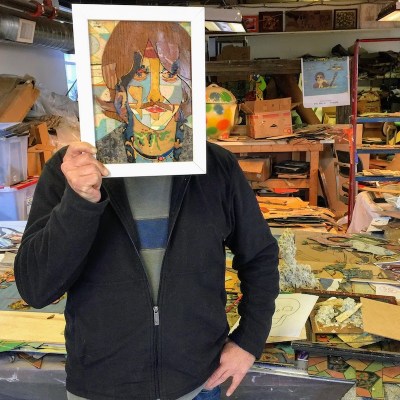artist Bill Miller holding his linoleum portrait of George Harrison in his Pittsburgh art studio