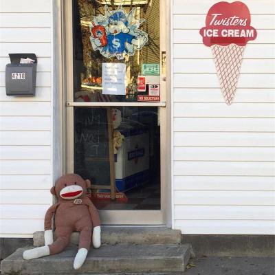 large stuffed animal made to look like a sock monkey laying in business doorway, Pittsburgh, PA