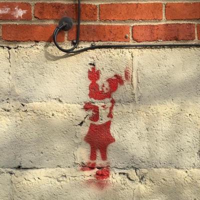 stencil image of person cradling a bomb painted on cinderblock wall, Pittsburgh, PA