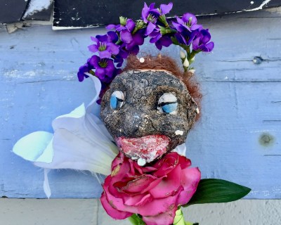 sculpture of black plaster head with fake flowers