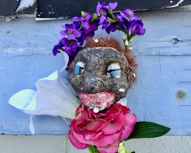 sculpture of black plaster head with fake flowers
