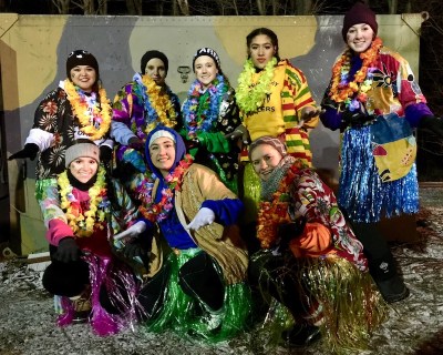 Women dressed in colorful Hawaiian shirts, skirts, and leis for Groundhog Day party