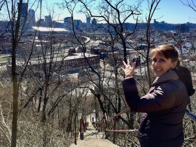 woman at top of long set of public stairs looking at a view of downtown Pittsburgh, PA