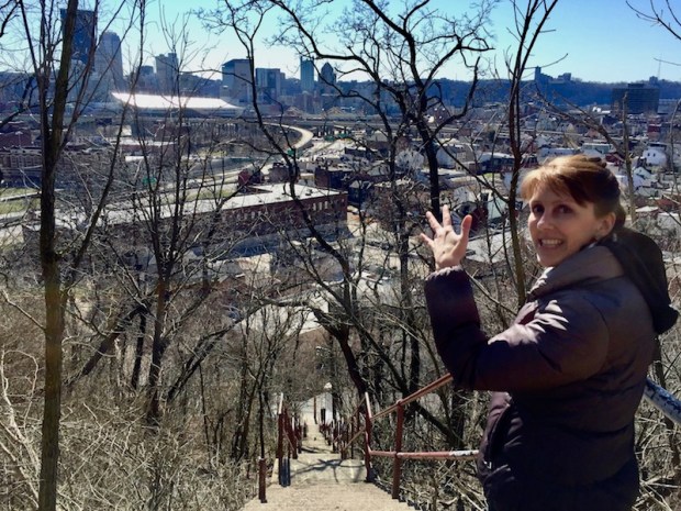 woman at top of long set of public stairs looking at a view of downtown Pittsburgh, PA