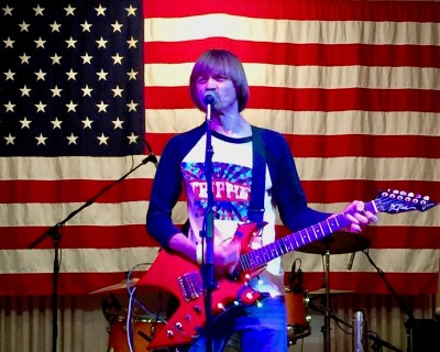 musician Weird Paul performing in front of an American flag, Pittsburgh, PA