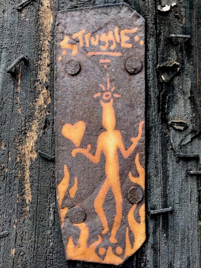 small painting of devil with heart on tin can nailed to utility pole, Pittsburgh, PA