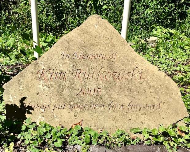 engraved stone with the text "In Memory of Kim Rutkowski, 2005, 'Always put your best foot forward'"