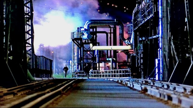 scene from "Striking Distance" as two characters race on foot at factory