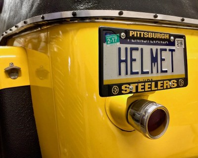 detail of 1950s era Willy's Jeepster showing "HELMET" personalized license plate and mounted bottle opener