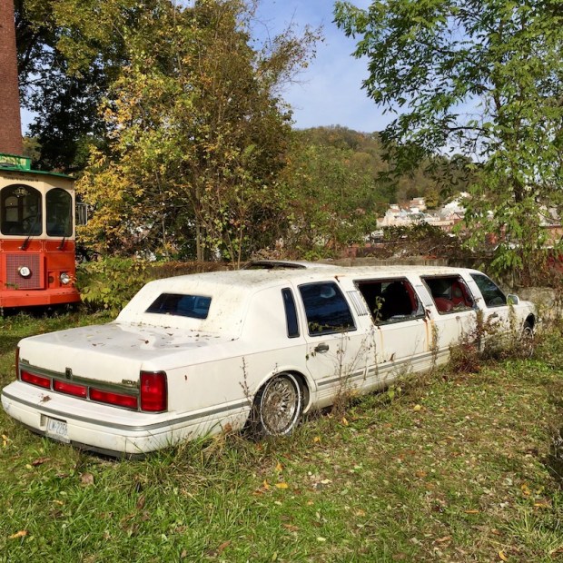 white stretch limousine with windows broken parked on grassy hillside, Millvale, PA
