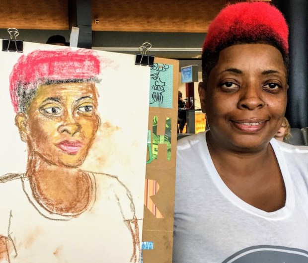 woman with dyed red hair holding partial portrait of herself