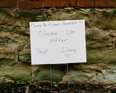handmade yard sign reading "Please be a good neighbor!!! Clean up after your dog"