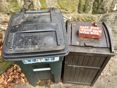 brick painted with message "Take dog poop home with dog" on outside garbage bins