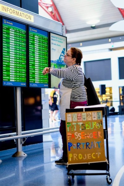 artist Kirsten Ervin looking at Pittsburgh airport's arrival information board