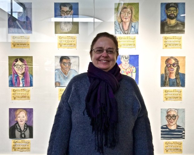 Artist Kirsten Ervin in front of chalk pastel portraits of airport passengers