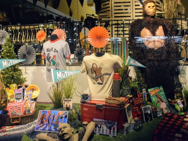 storefront window display featuring novelty items associated with the Mothman, Bigfoot, and zombies