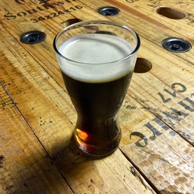dark beer in glass on rough wooden table