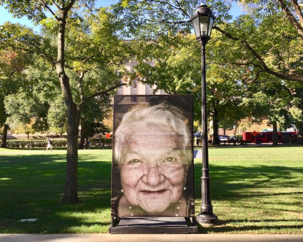 large portrait of Holocaust survivor mounted on exterior display at the University of Pittsburgh campus as part of Luigi Toscano's "Lest We Forget" portrait series