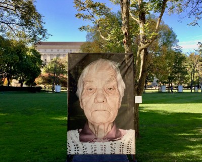 large portrait of Holocaust survivor mounted on exterior display at the University of Pittsburgh campus as part of Luigi Toscano's "Lest We Forget" portrait series