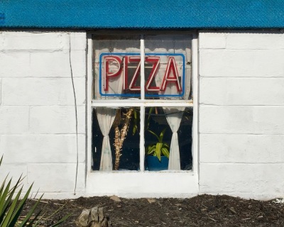 basement window with neon "PIZZA" sign