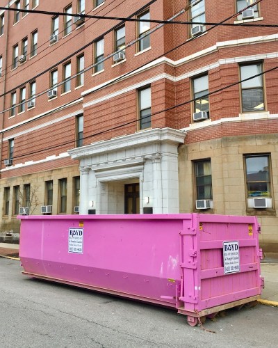 pink dumpster in front of hospital entrance